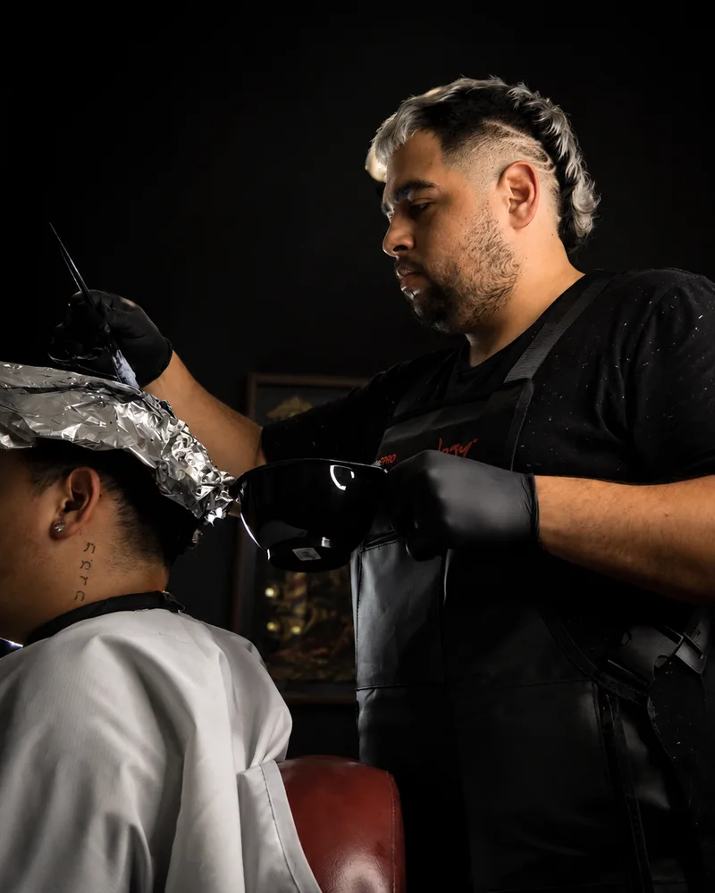 El barbero aplicando color a un cliente